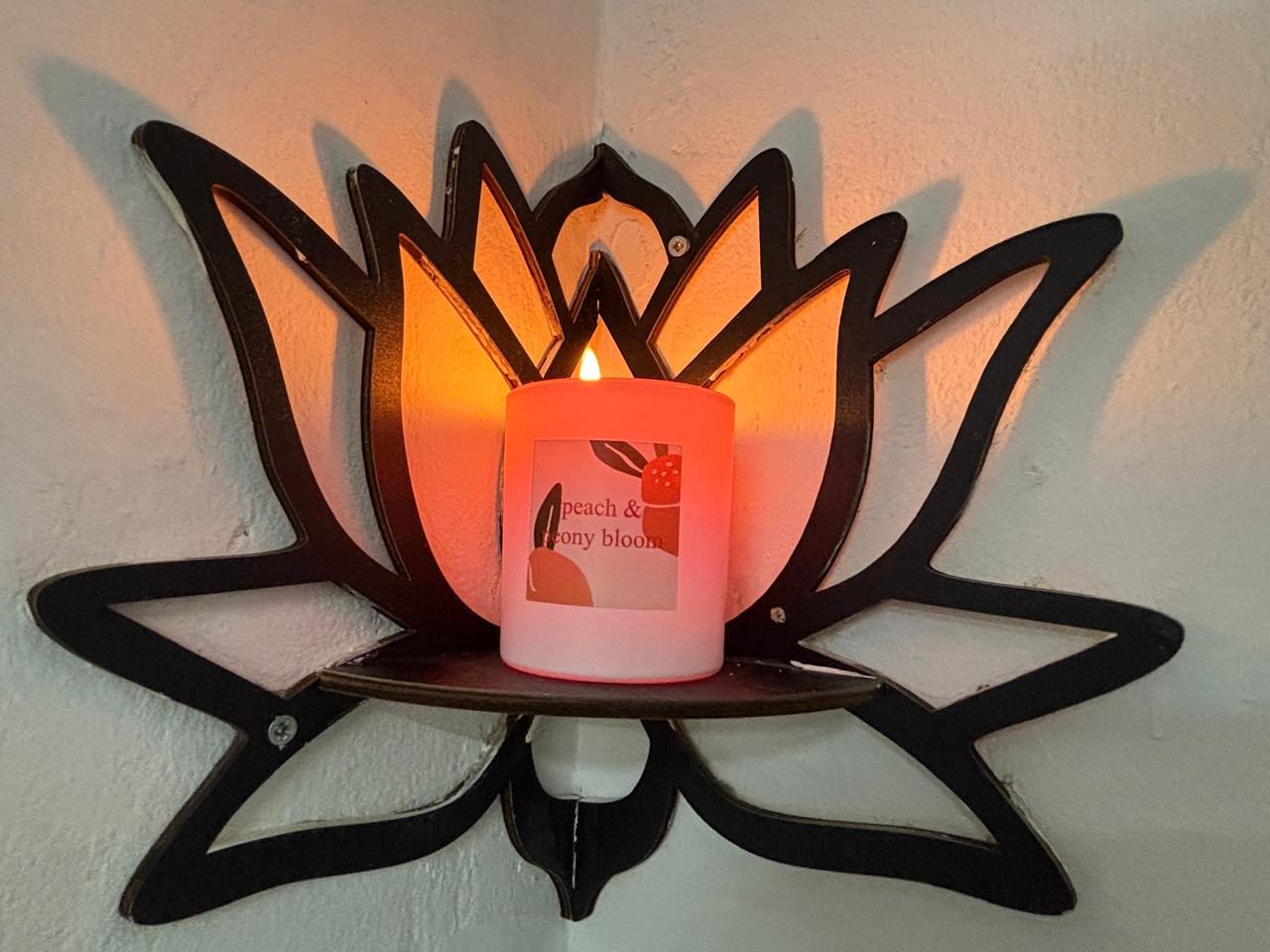 A candle glowing inside a lotus-shaped wall sconce