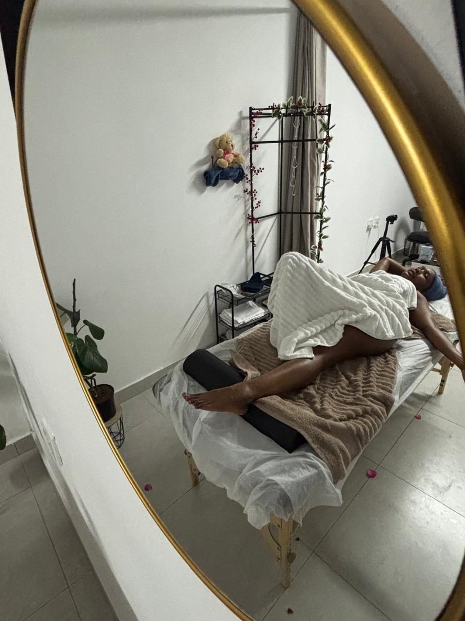 Reflection of a client resting on the treatment table, seen through a round mirror