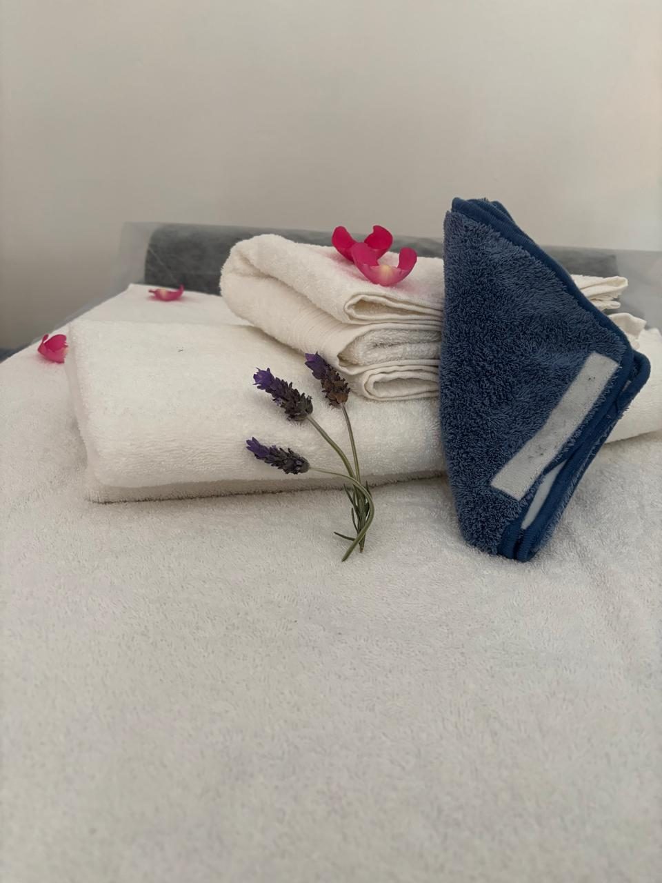Folded towels beside a sprig of fresh lavender